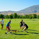 four men playing spikeball at the park
